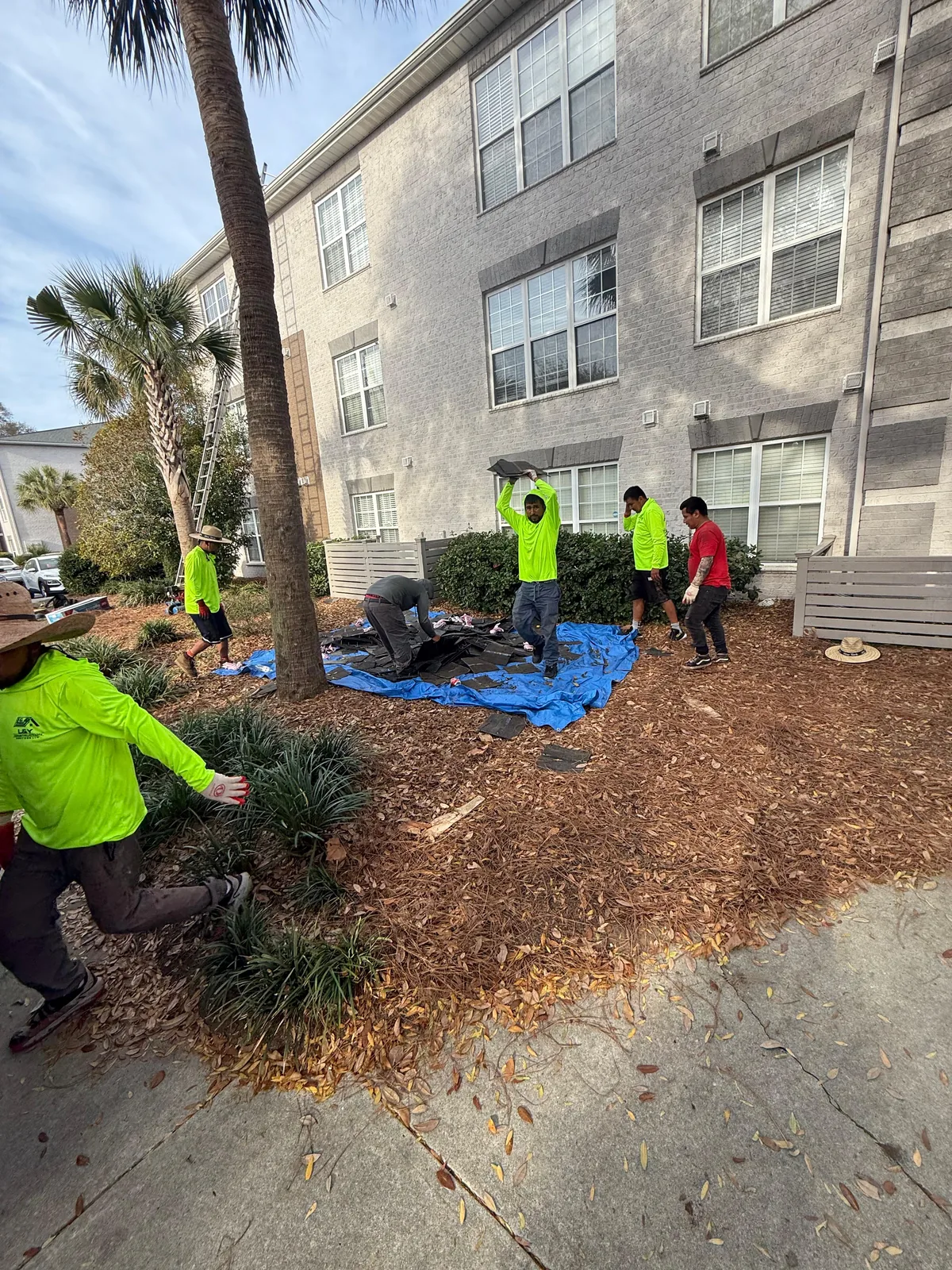 Crew working on exterior apartment property updates near landscaping