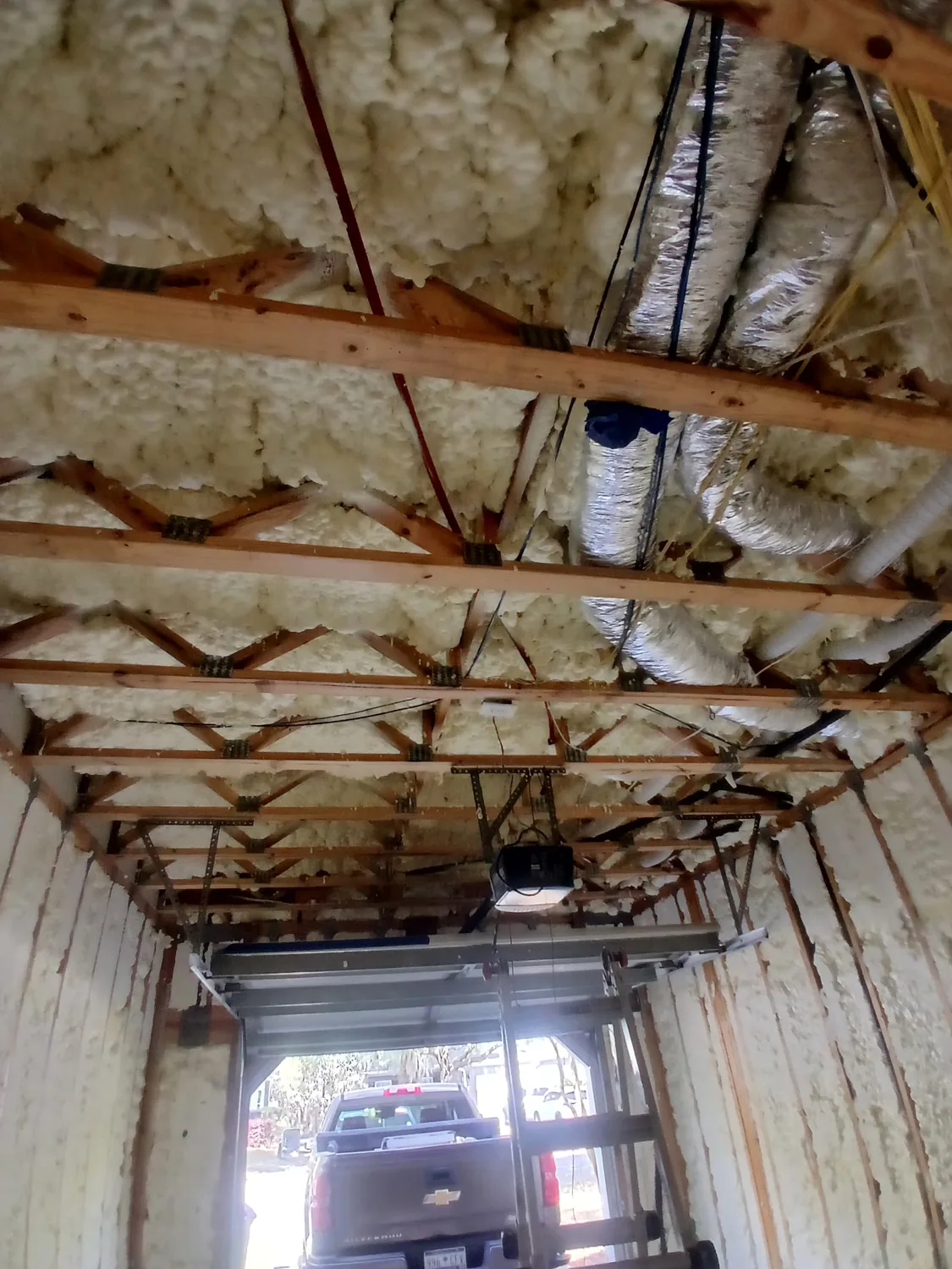 Garage ceiling framing with spray foam insulation and exposed mechanical lines