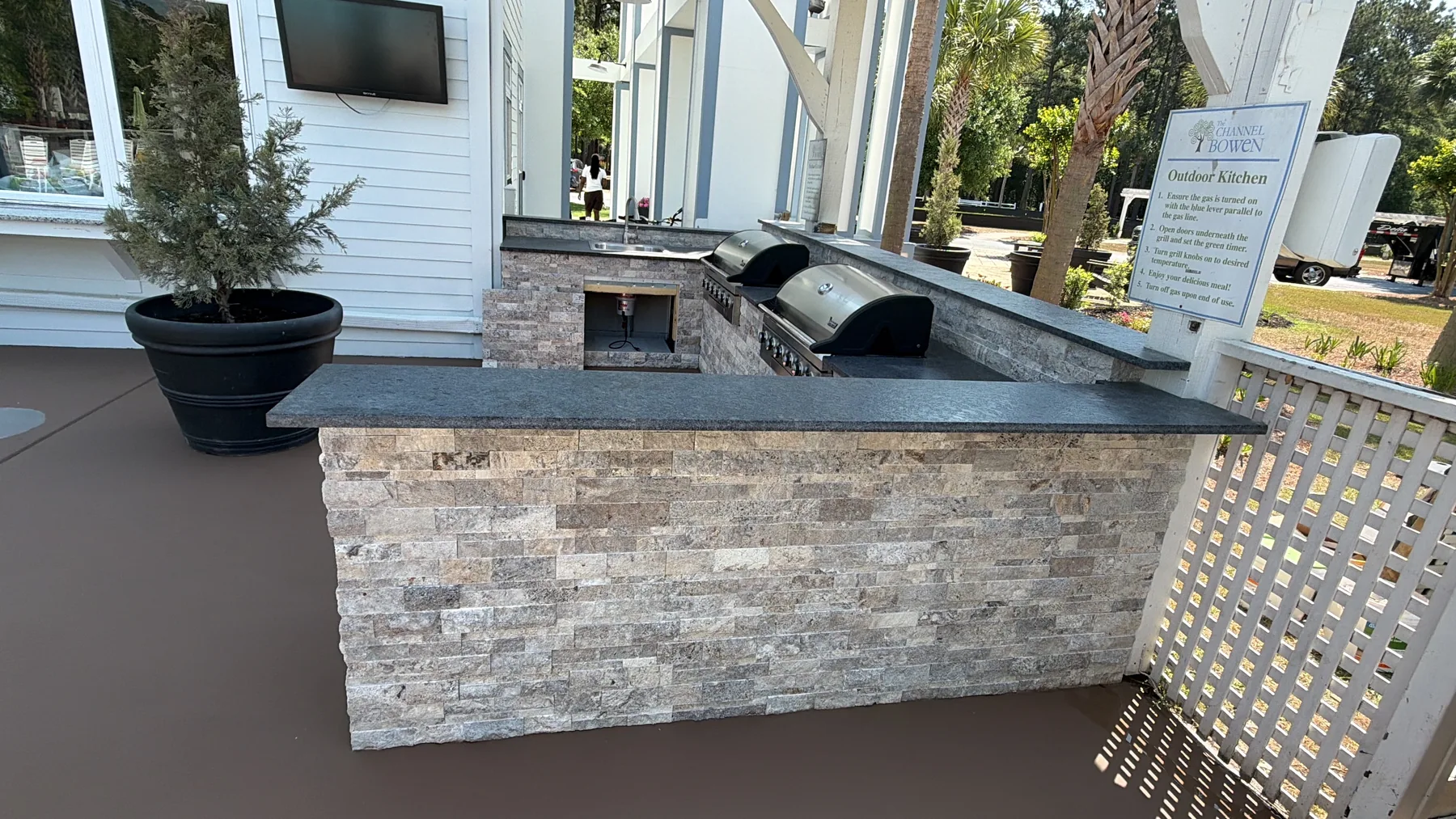 Finished outdoor kitchen with stone surround, countertop, and built-in grills