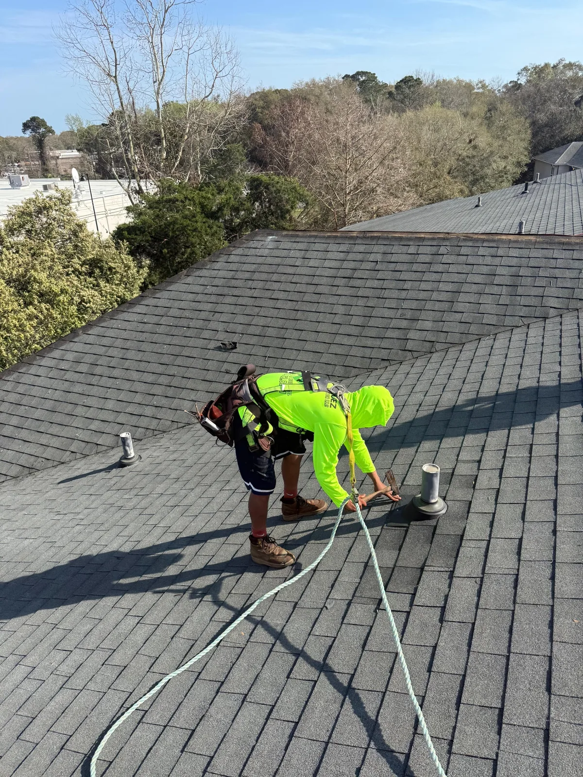 Worker performing roof detail work on an asphalt shingle roof
