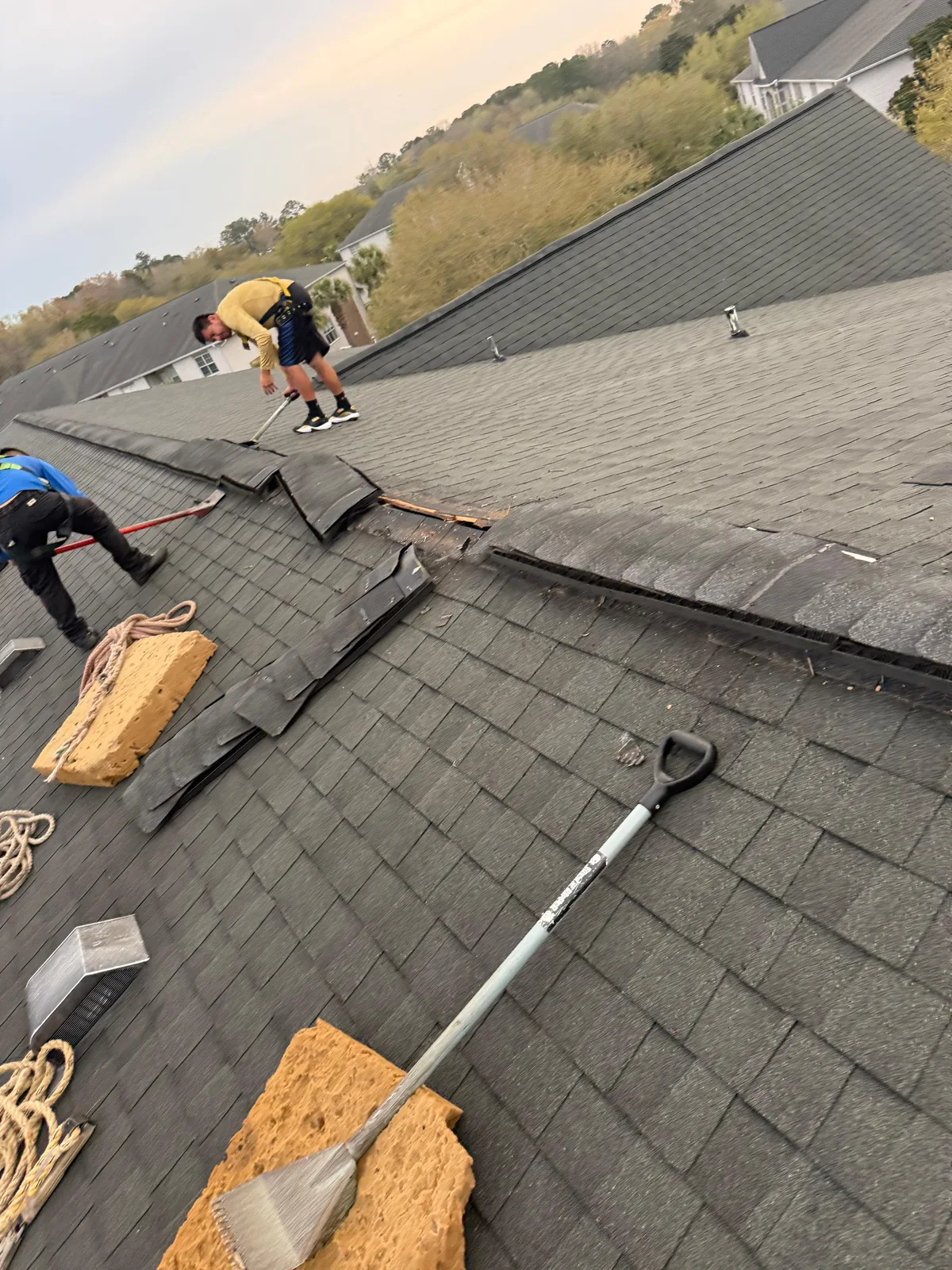 Roof repair worksite with tools and materials on shingles